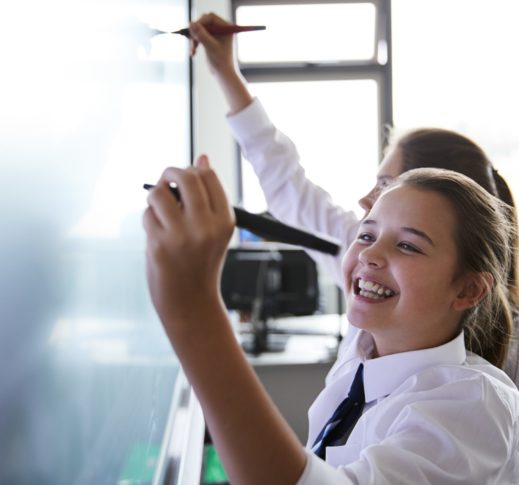 Female High School Students Wearing Uniform Using Interactive Whiteboard During Lesson